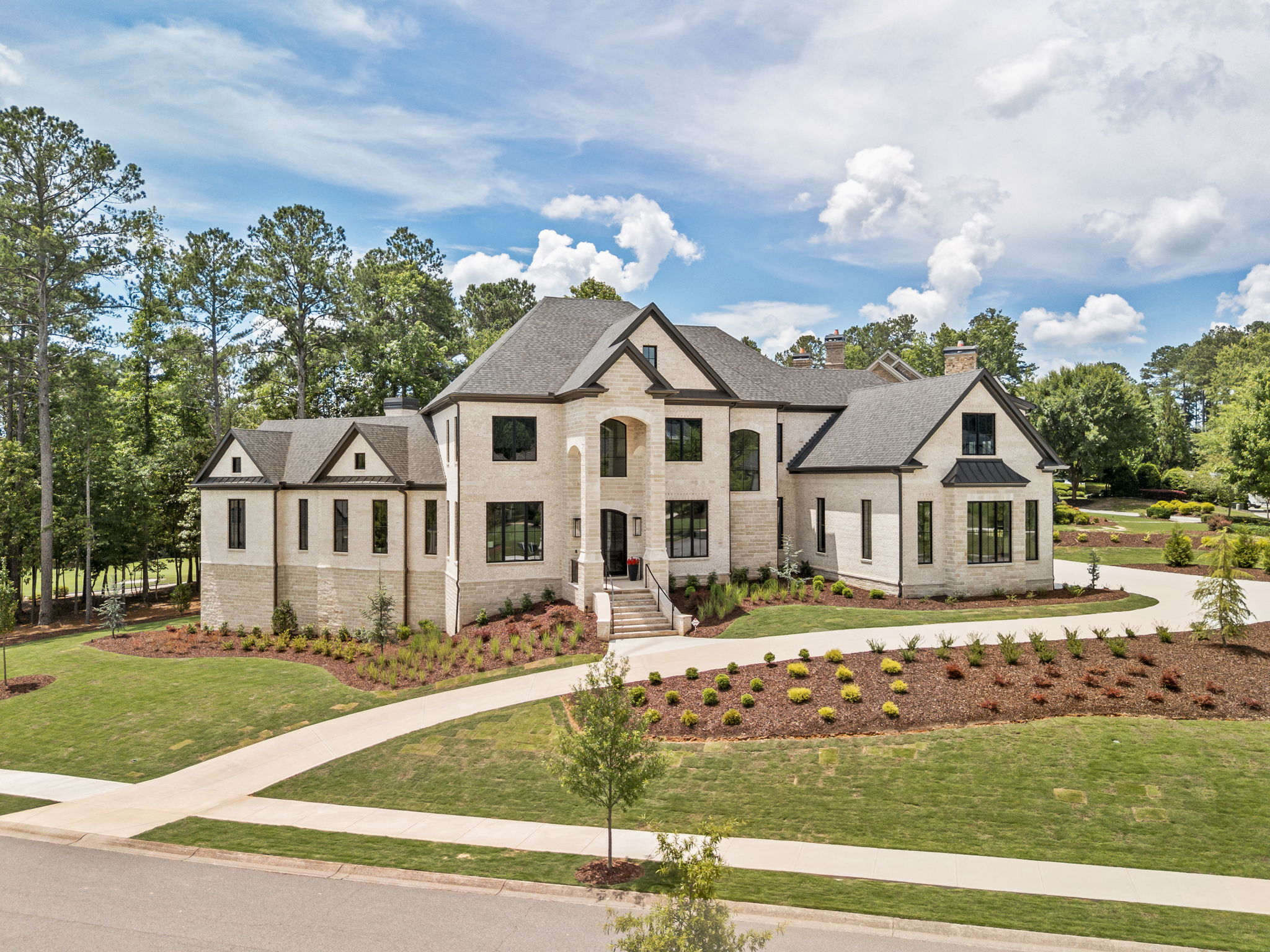 Aerial view of a finished luxury custom home with manicured landscaping